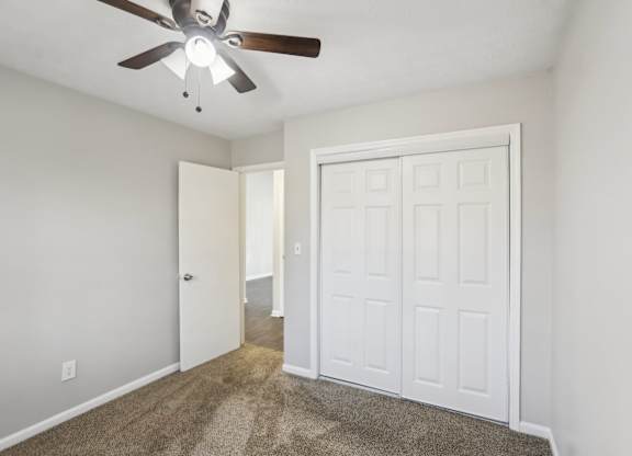 A room with a ceiling fan and a white door.