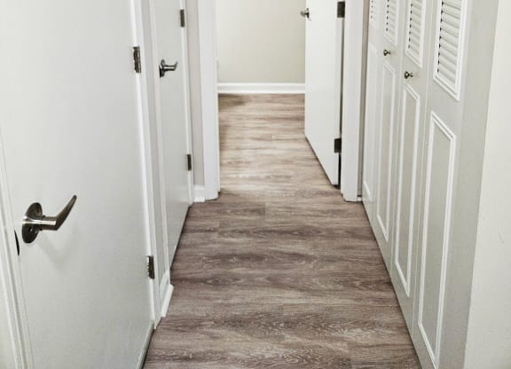 hallway with white closet doors and a wood floor