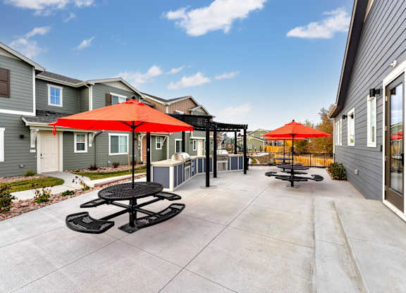 A patio with a table and chairs and umbrellas.
