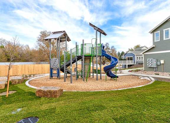 A playground with a green slide and a wooden structure.
