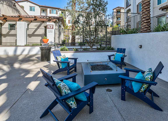 A patio with blue chairs and a table with a tray of fruit on it.