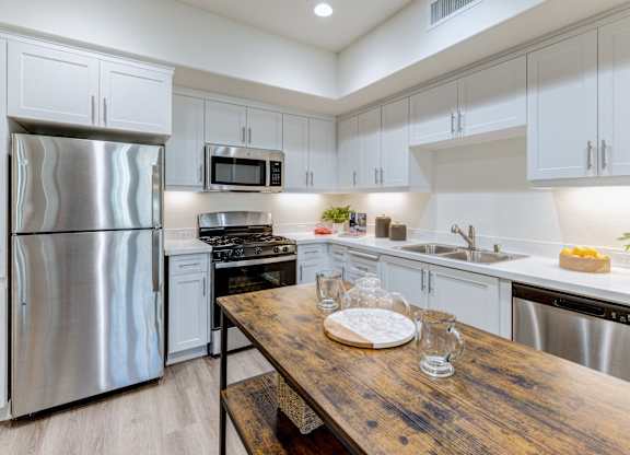 A kitchen with a wooden table and stainless steel appliances.