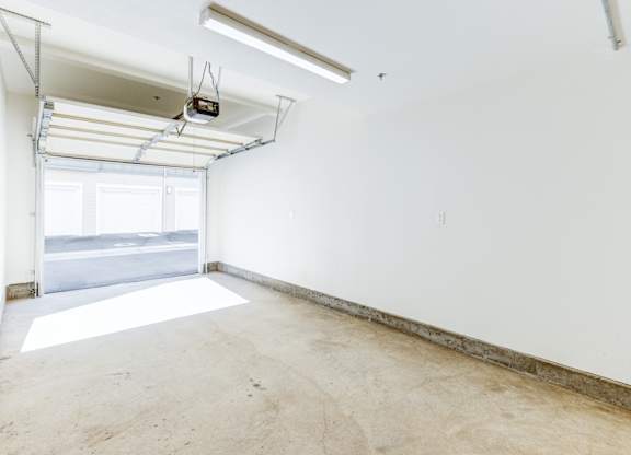 A large empty room with a window and a white wall.