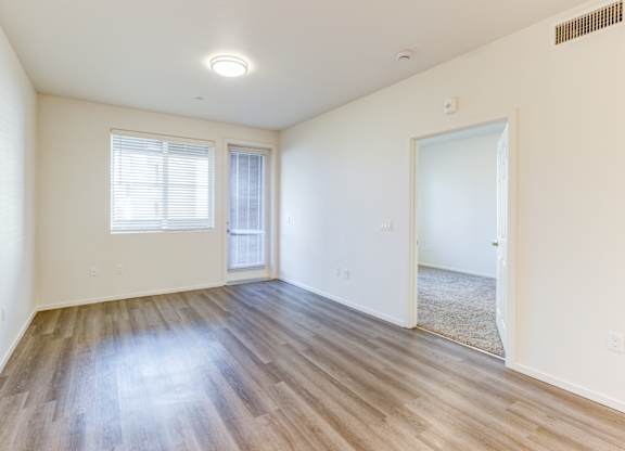A room with wooden flooring and a window with blinds.