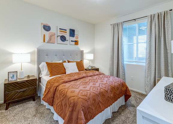 A bedroom with a bed, nightstand, and a painting on the wall.