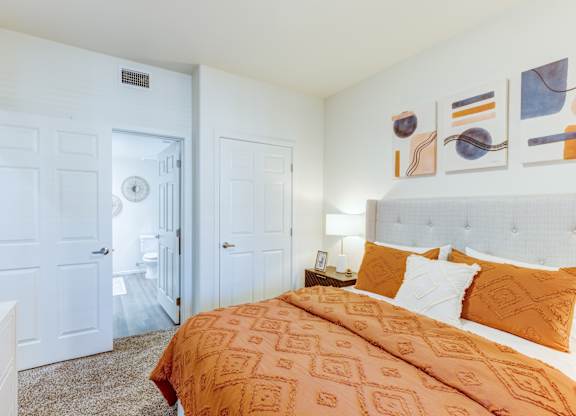 A bedroom with a bed, two doors, and a nightstand.