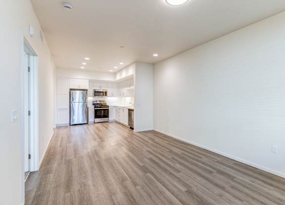 A spacious room with wooden flooring and white walls.