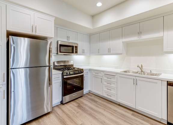 A modern kitchen with white cabinets and stainless steel appliances.