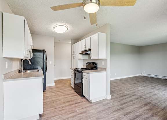 A kitchen with white cabinets and a black refrigerator.