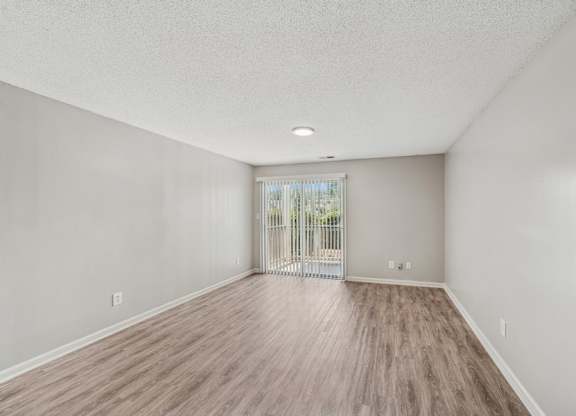 A room with wooden flooring and a sliding glass door.