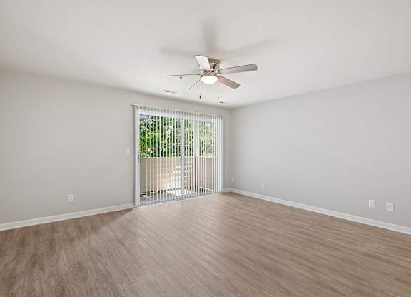 A room with a ceiling fan and sliding glass doors.