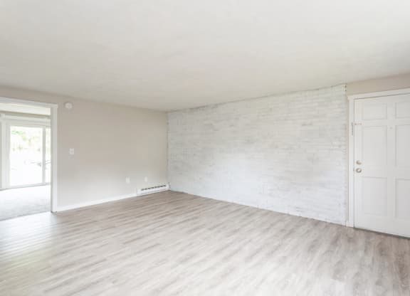an empty living room with a white wall and wood floors at Stonebridge, Ellington