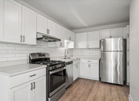 an all white kitchen with stainless steel appliances and white cabinets at The Reserve on Washington, Illinois