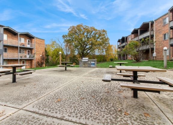 an empty park with picnic tables in front of apartment buildings at River Oaks, North Aurora