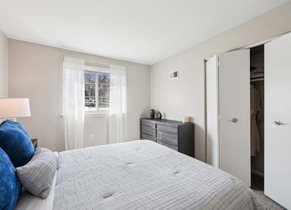 A bedroom with a large bed and a window with curtains.