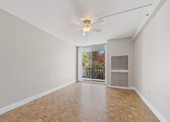 A room with a ceiling fan and a sliding glass door leading to a balcony.