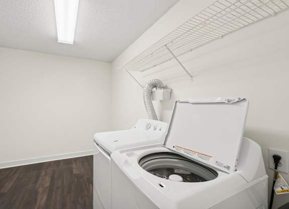 A white washing machine in a small room with wood flooring.