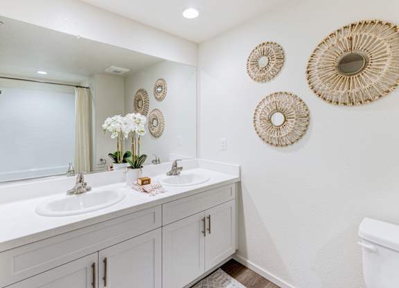 A white bathroom with two sinks and a toilet.