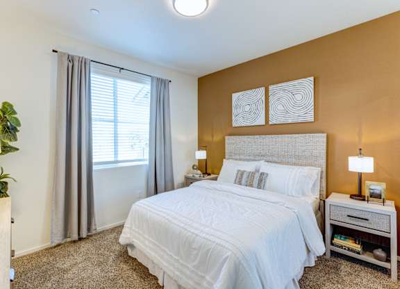 A bedroom with a large bed and a window with curtains.