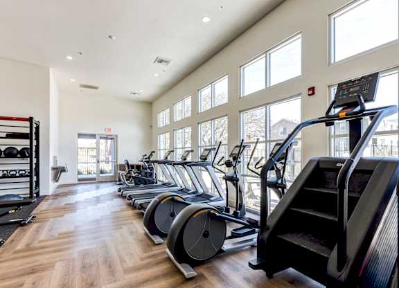A gym with treadmills, elliptical machines, and a weight rack.