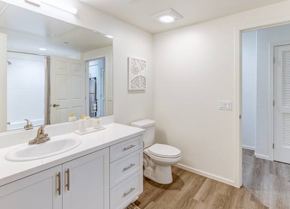 A white bathroom with a toilet, sink, and mirror.