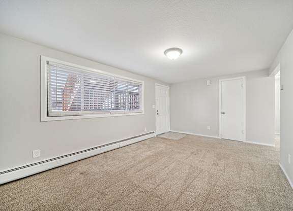 A room with a carpeted floor and a window with blinds.