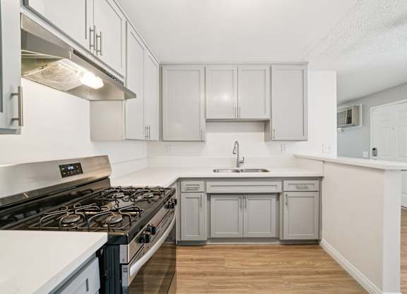 A kitchen with a stove top oven and a sink.