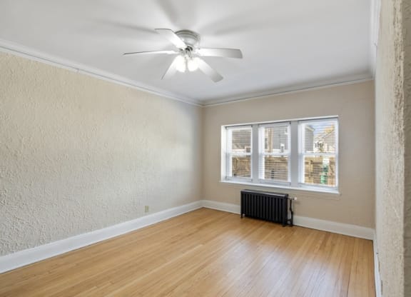 an empty living room with a ceiling fan and a window