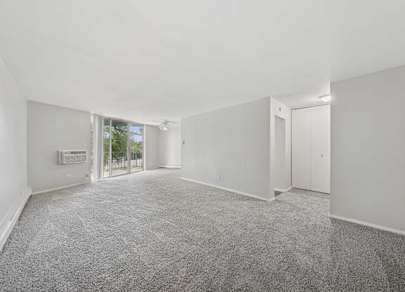 A spacious room with grey carpeting and white walls.