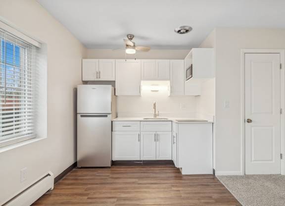 A kitchen with white cabinets and a stainless steel refrigerator.