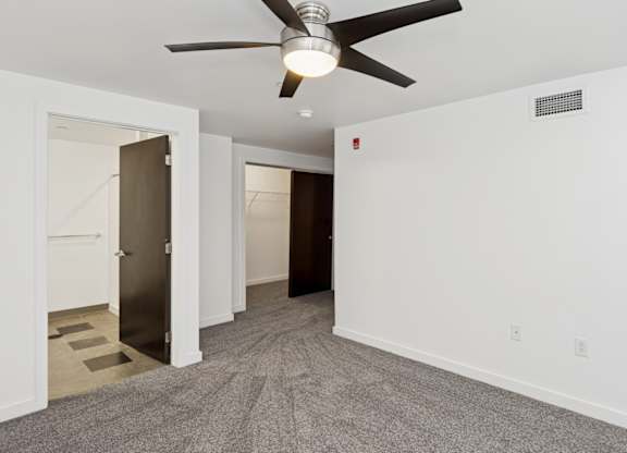 A room with a ceiling fan and carpeted floor.