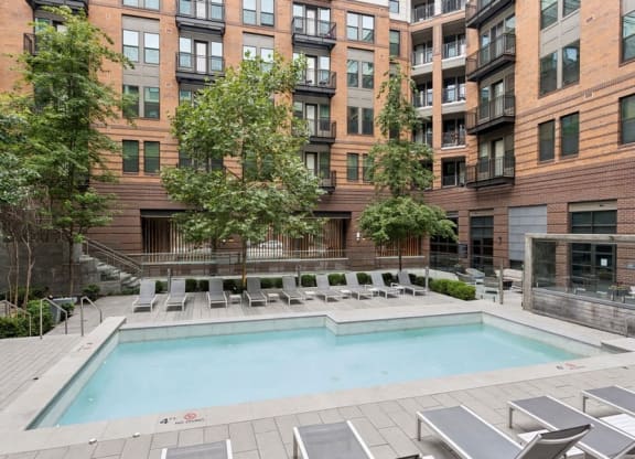 a swimming pool with chairs in front of a building