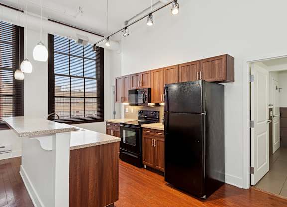A kitchen with a black refrigerator and wooden cabinets.
