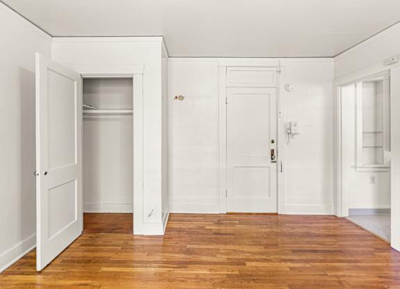 A room with a closet and wooden floors.