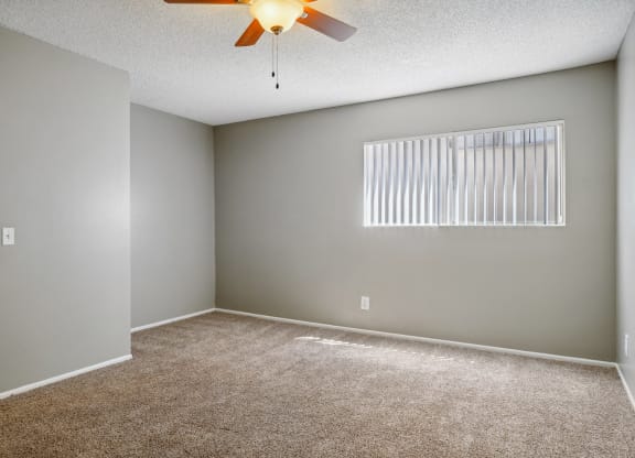 an empty living room with a ceiling fan and a window