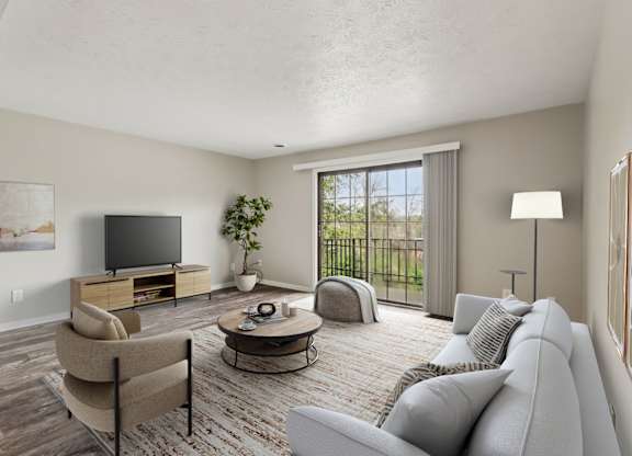 A living room with a grey couch, a chair, a coffee table, a television, and a potted plant.