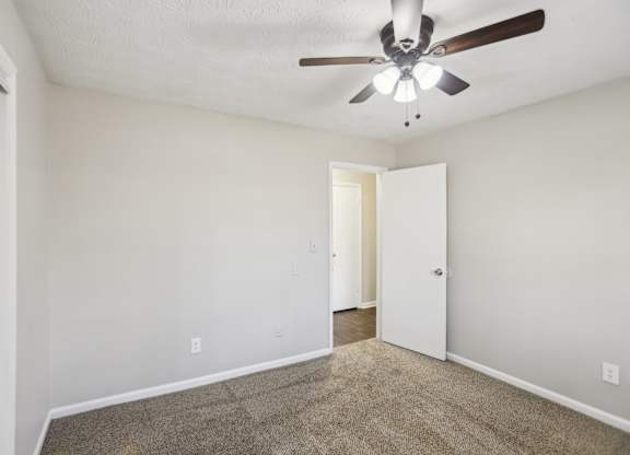 A room with a ceiling fan and carpeted floor.