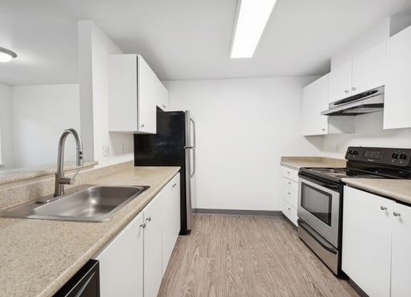 a spacious kitchen with stainless steel ktichen appliances, white cabinets, and wood flooring at Murrayhill Park, Beaverton Oregon