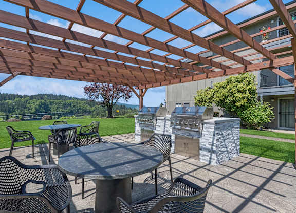 A patio with a table and chairs under a wooden pergola.