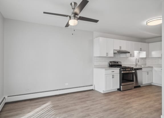 an empty living room with a ceiling fan and a kitchen at The Reserve on Washington, Naperville, 60565