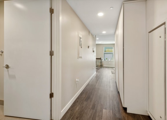 a hallway with white walls and wooden floors and white doors at The Rowe, Grand Rapids