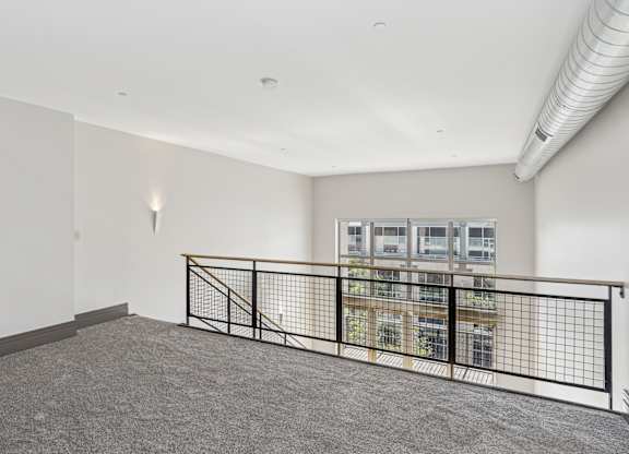 A room with a grey carpet and a black railing.