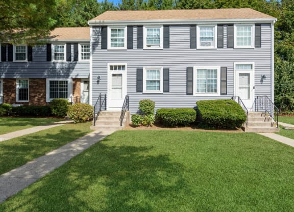the front of the apartments with a lawn and a pathway at Arbor Commons