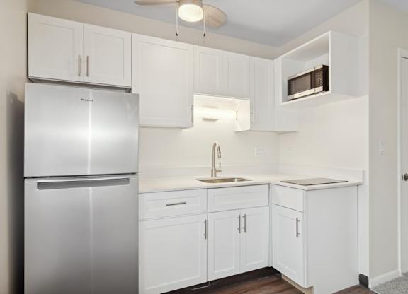 A kitchen with white cabinets and a stainless steel refrigerator.