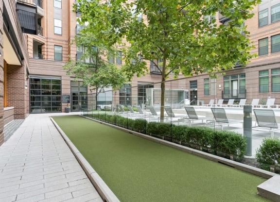 a courtyard with grass and chairs in front of a building