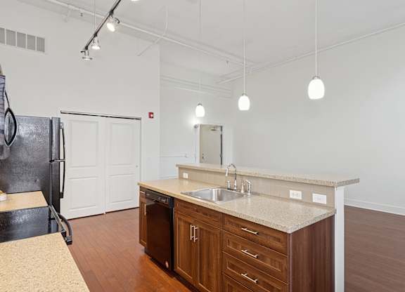 A kitchen with a sink, cabinets, and a refrigerator.