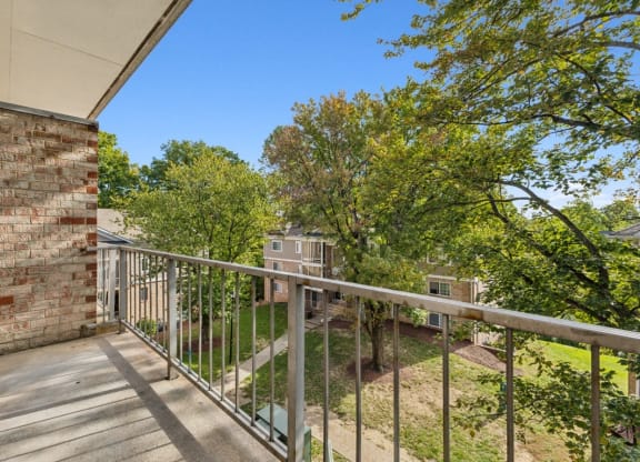 a balcony with a wooden railing and trees and a brick building at Briarwood Apartments, Dumfries, Virginia