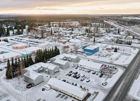 A small town with buildings and cars is surrounded by snow.