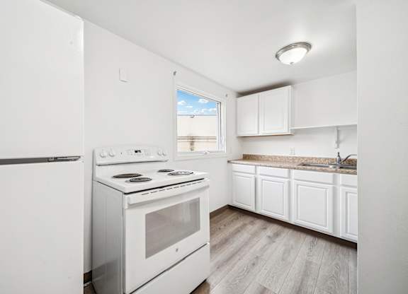 A white kitchen with a stove and a refrigerator.