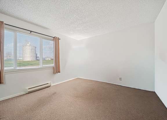 A room with a window and a carpeted floor.